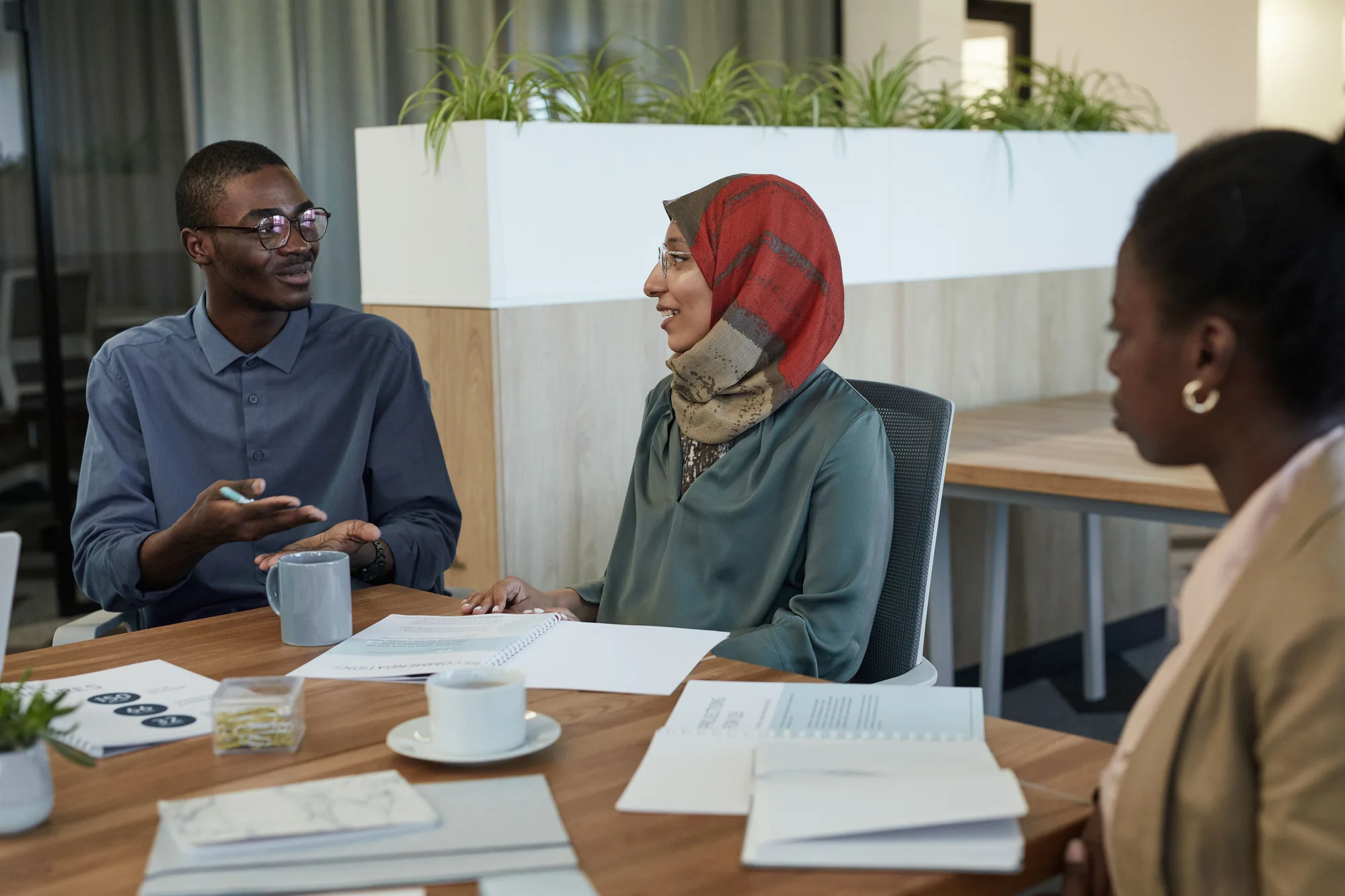 An African professional discussing documents with colleagues in a modern office